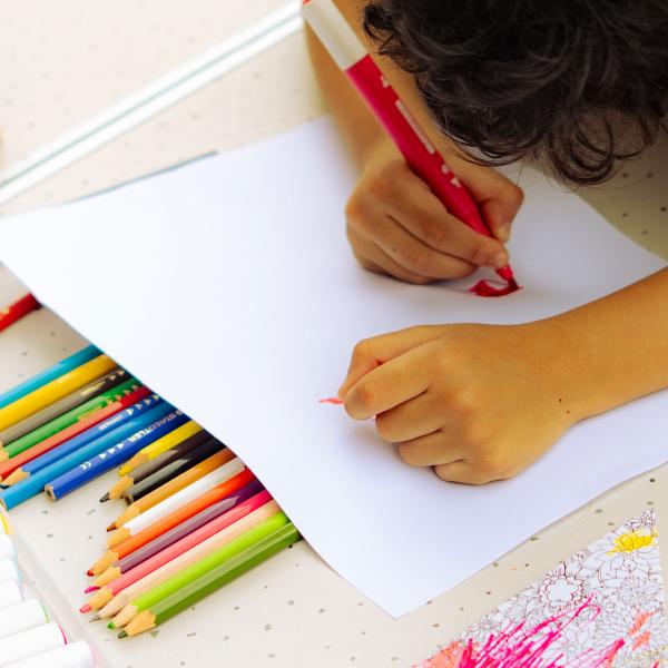 © Solveig Augereau Un enfant dessine à une table. Il y a plein de crayons et de feutres.
